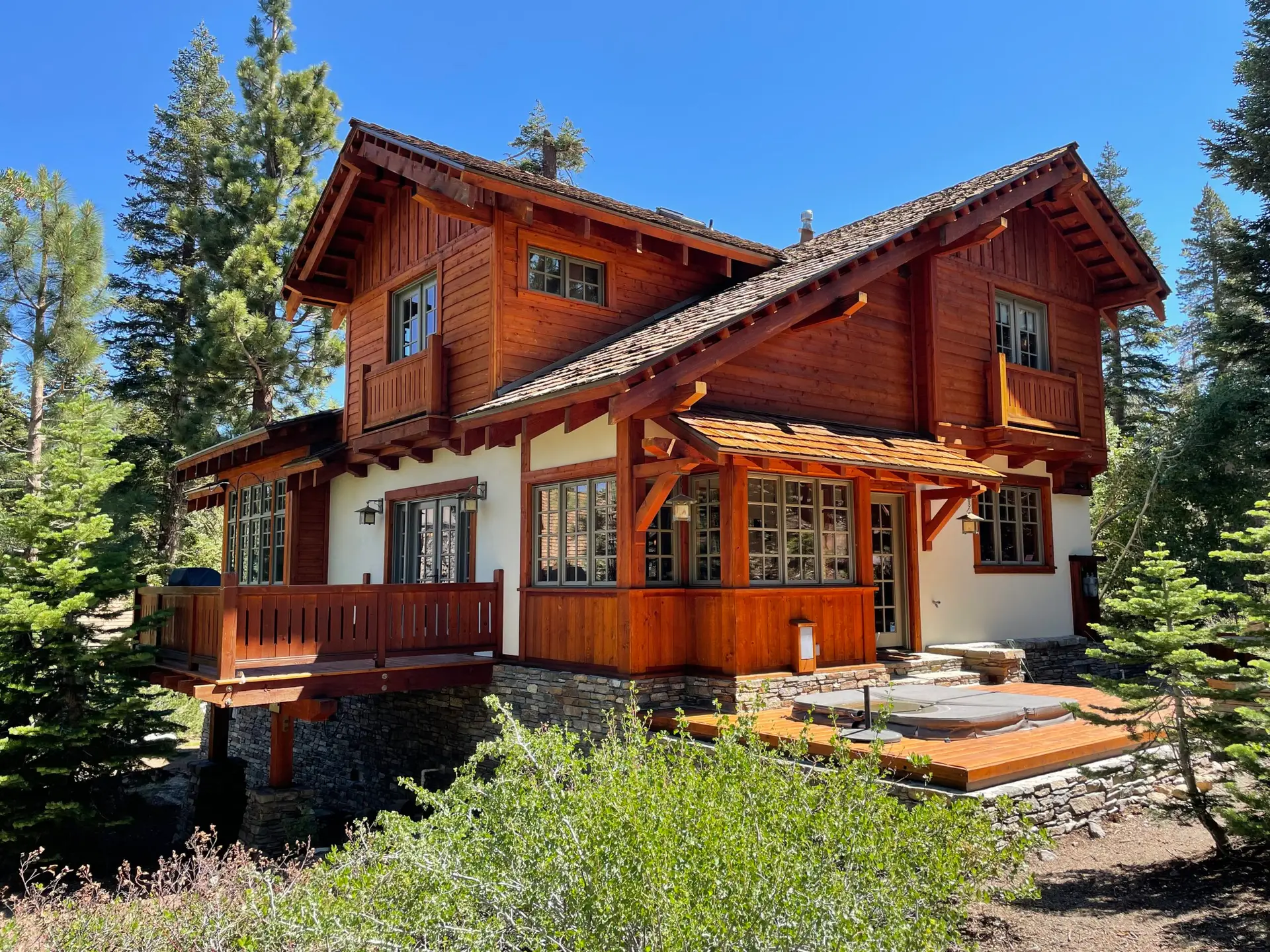 Stained timber mountain home surrounded by pine trees