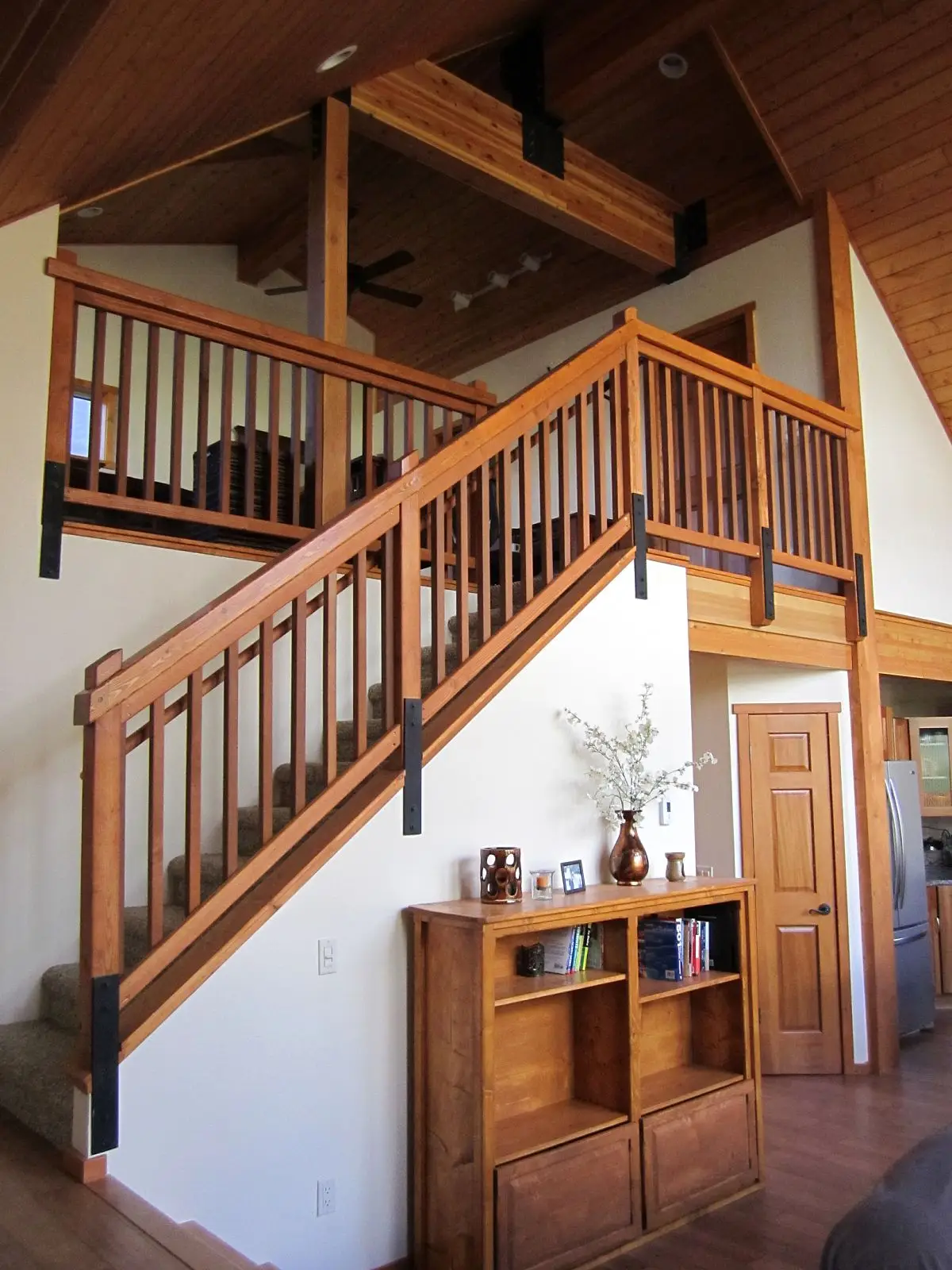 Wood staircase and railing in a bright home with a vaulted ceiling